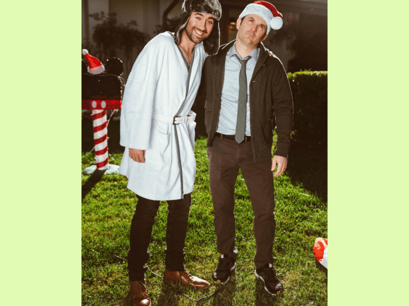The Bibel Team two men standing on a lawn, one in a Santa hat, the other in a hunting hat